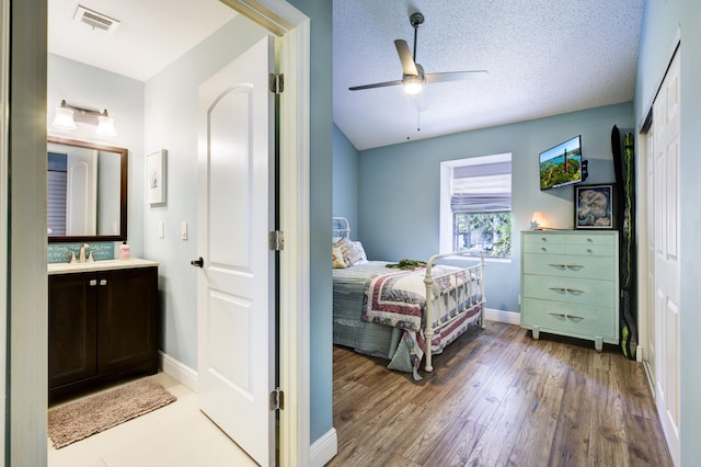 bedroom with baseboards, a sink, light wood-style flooring, a closet, and ceiling fan