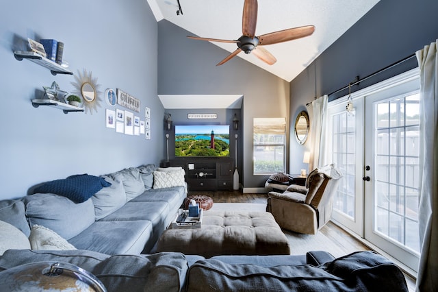 living area with high vaulted ceiling, a ceiling fan, plenty of natural light, french doors, and wood finished floors