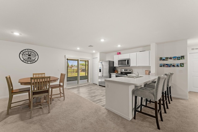 5248 NW Gamma St, Port Saint Lucie, FL 34986 - kitchen featuring stainless steel appliances, a sink, a breakfast bar, recessed lighting, and white cabinets