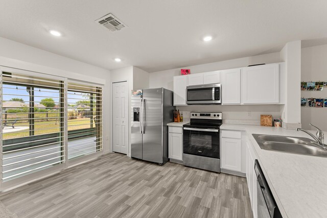 5248 NW Gamma St, Port Saint Lucie, FL 34986 - kitchen with stainless steel appliances, a sink, light countertops, white cabinetry, and recessed lighting