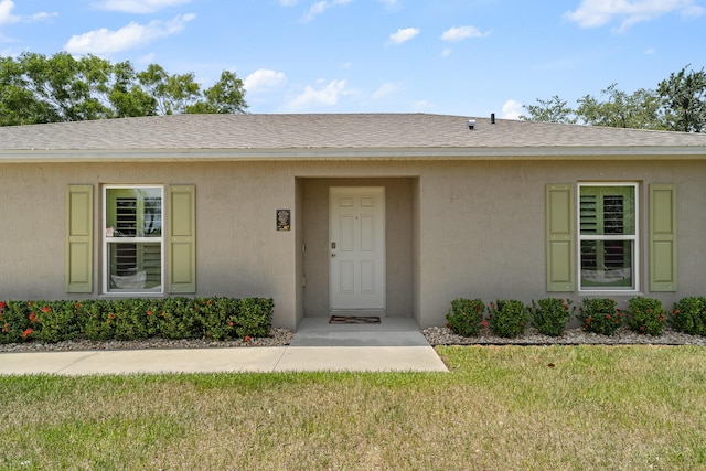 5248 NW Gamma St, Port Saint Lucie, FL 34986 - entrance to property featuring a yard, stucco siding, and roof with shingles