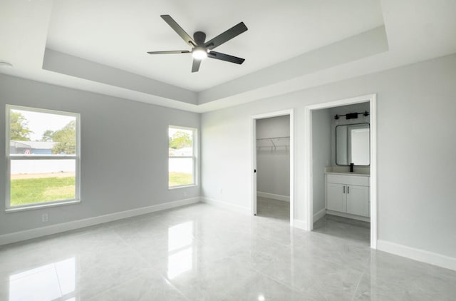 12180 SE 89th Ter, Belleview, FL 34420 - unfurnished bedroom with a tray ceiling, baseboards, a spacious closet, and ensuite bath