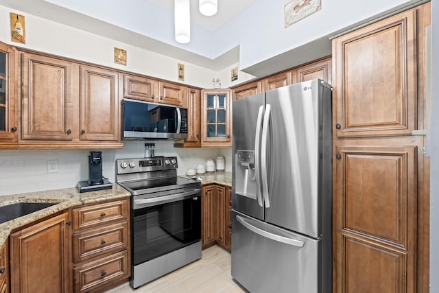 802 W Windward Way Unit 304, Lantana, FL 33462 - kitchen featuring stainless steel appliances, brown cabinets, light stone counters, and glass insert cabinets