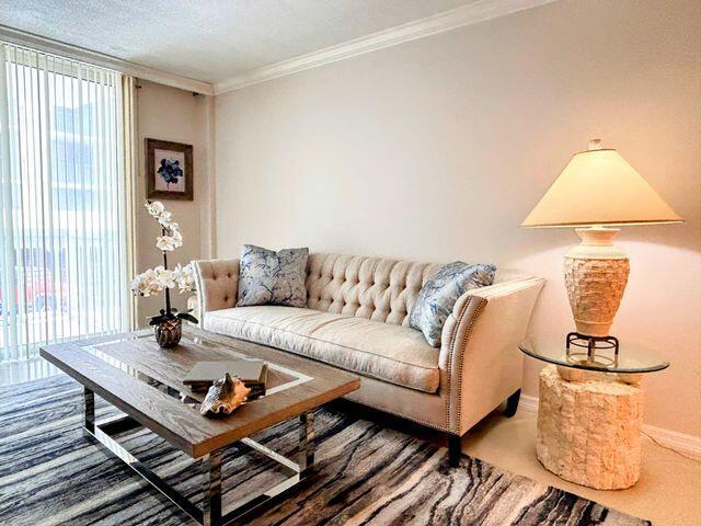 living room featuring baseboards, ornamental molding, and carpet floors