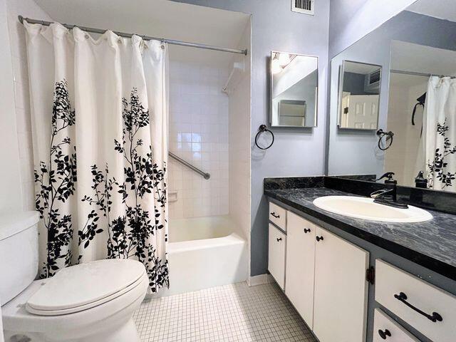 bathroom with toilet, vanity, visible vents, tile patterned flooring, and shower / tub combo
