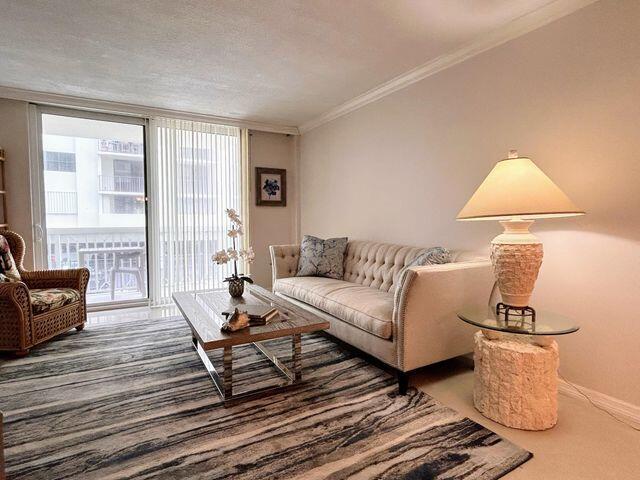 carpeted living area featuring crown molding and baseboards