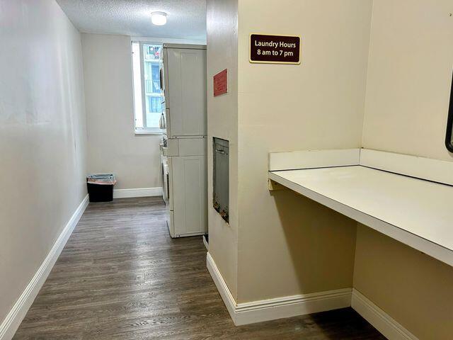 hall featuring baseboards, a textured ceiling, and dark wood-type flooring