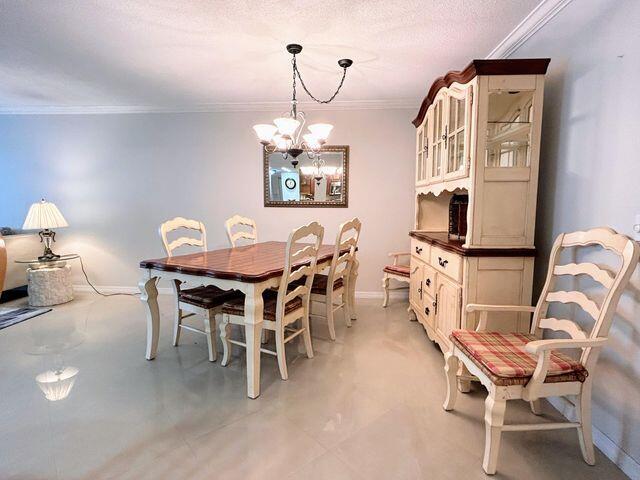 dining area featuring baseboards, ornamental molding, and a notable chandelier