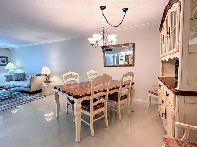 dining space with baseboards, ornamental molding, and a notable chandelier