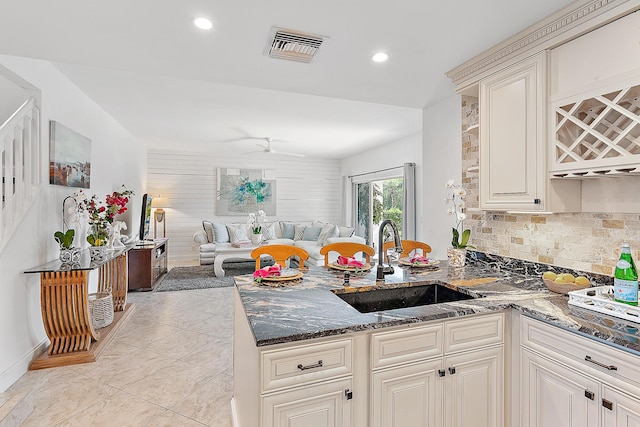 2703 Fairway Dr N, Jupiter, FL 33477 - kitchen with open floor plan, a peninsula, dark stone countertops, tasteful backsplash, and a ceiling fan