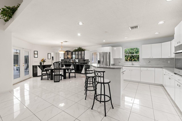 kitchen featuring stainless steel appliances, a center island, a sink, decorative backsplash, and recessed lighting