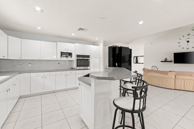 kitchen featuring appliances with stainless steel finishes, a kitchen breakfast bar, a kitchen island, tasteful backsplash, and recessed lighting