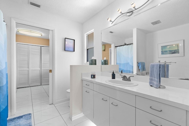 bathroom with toilet, a textured ceiling, vanity, a closet, and baseboards