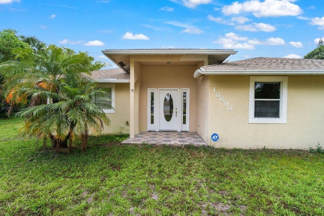 doorway to property with stucco siding and a lawn