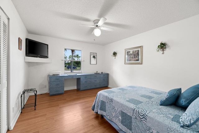 bedroom featuring wood finished floors, a textured ceiling, an office area, ceiling fan, and baseboards
