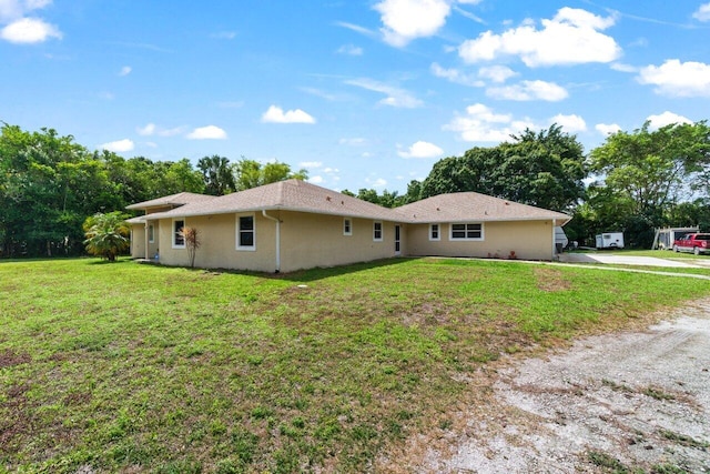back of property with a lawn, stucco siding, and driveway