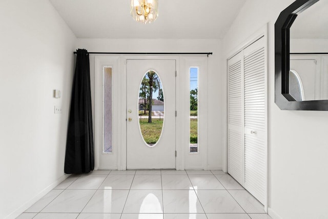 foyer featuring plenty of natural light, baseboards, and a chandelier