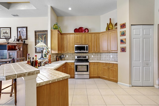 1815 Waldorf Dr, Royal Palm Beach, FL 33411 - kitchen with appliances with stainless steel finishes, a sink, light tile patterned floors, a peninsula, and recessed lighting