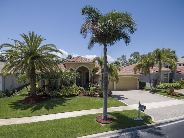 1815 Waldorf Dr, Royal Palm Beach, FL 33411 - mediterranean / spanish home with decorative driveway, an attached garage, a tiled roof, stucco siding, and a front lawn