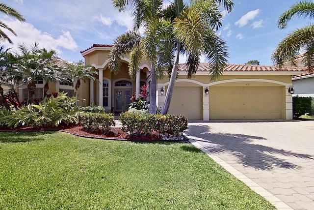 1815 Waldorf Dr, Royal Palm Beach, FL 33411 - mediterranean / spanish-style home featuring stucco siding, a garage, a front yard, a tile roof, and driveway