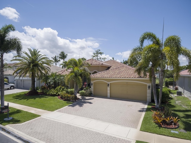 1815 Waldorf Dr, Royal Palm Beach, FL 33411 - mediterranean / spanish-style house featuring an attached garage, stucco siding, decorative driveway, a front yard, and a tile roof