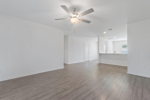 unfurnished living room featuring wood finished floors, a ceiling fan, baseboards, and recessed lighting