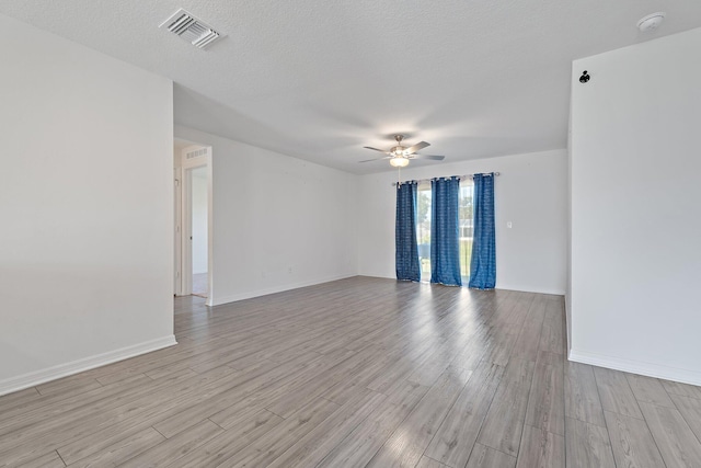 empty room featuring ceiling fan, light wood finished floors, baseboards, a smoke detector, and a textured ceiling