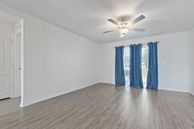 spare room with ceiling fan, wood finished floors, and baseboards