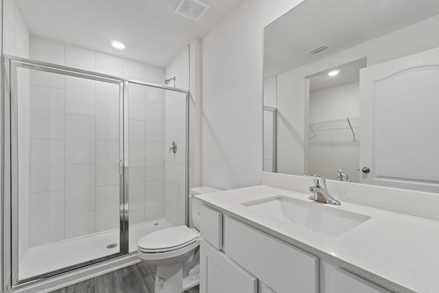 full bath with toilet, a shower stall, wood finished floors, vanity, and recessed lighting