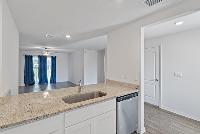 kitchen with stainless steel dishwasher, a sink, light stone counters, white cabinets, and recessed lighting