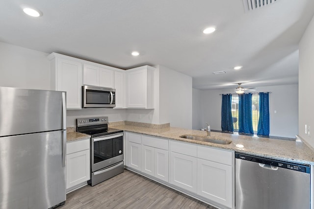 kitchen featuring stainless steel appliances, a sink, white cabinets, light stone counters, and recessed lighting