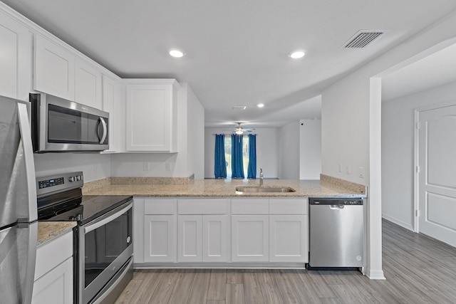 kitchen featuring stainless steel appliances, a sink, light wood-type flooring, white cabinetry, and recessed lighting