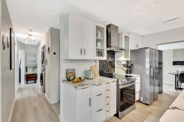 115 W 31st Ct, Riviera Beach, FL 33404 - kitchen featuring stacked washer / dryer, visible vents, wall chimney exhaust hood, light wood-style floors, and appliances with stainless steel finishes