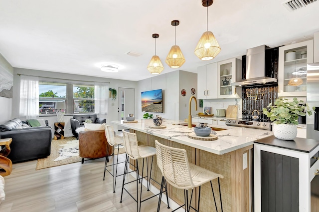 115 W 31st Ct, Riviera Beach, FL 33404 - kitchen featuring a sink, wall chimney exhaust hood, open floor plan, white cabinetry, and visible vents