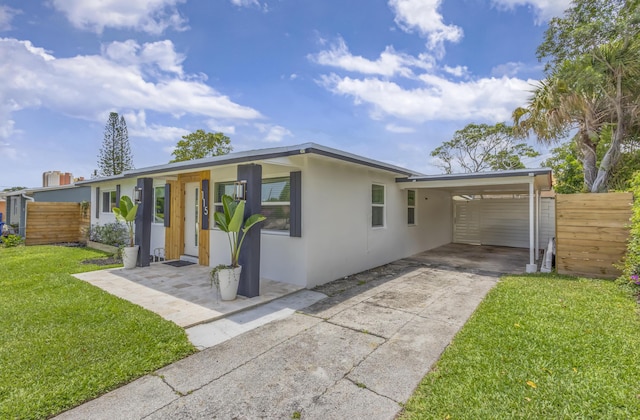 115 W 31st Ct, Riviera Beach, FL 33404 - view of front of property featuring fence, stucco siding, concrete driveway, a front lawn, and a carport