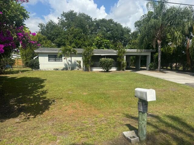 2403 Kelly Ct, Fort Pierce, FL 34982 - view of front of house with concrete driveway, a front yard, and a carport