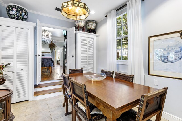 335 Monroe Dr, West Palm Beach, FL 33405 - dining space featuring light tile patterned flooring, crown molding, and a chandelier