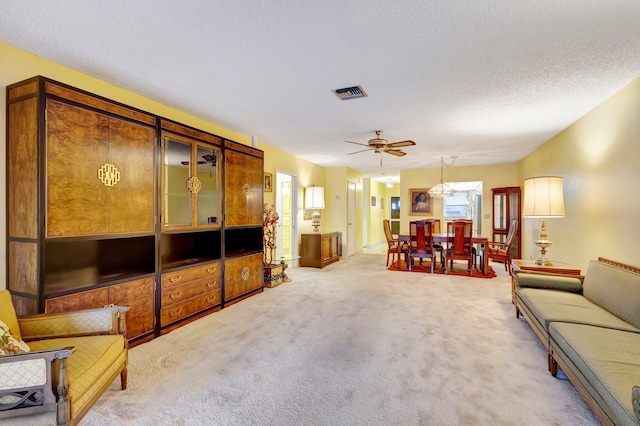 living room with light colored carpet, a ceiling fan, and a textured ceiling