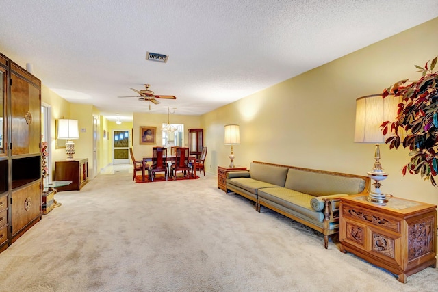 living room with light carpet, ceiling fan, and a textured ceiling