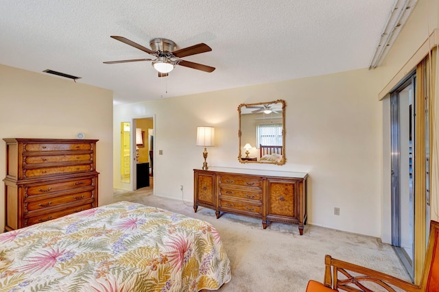 bedroom featuring light colored carpet, a textured ceiling, a ceiling fan, and ensuite bath