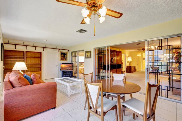 dining space with a ceiling fan, light tile patterned floors, and a textured ceiling