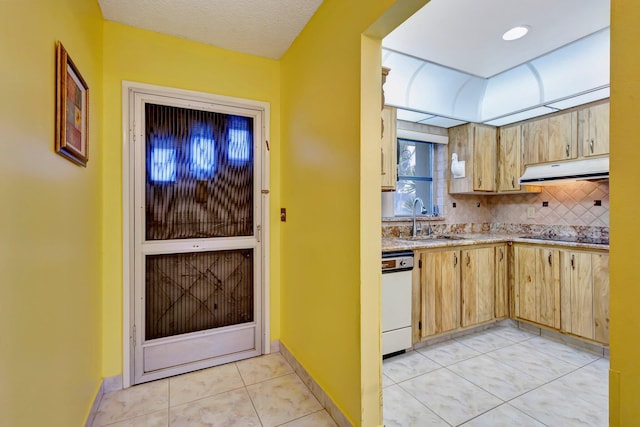 kitchen featuring under cabinet range hood, a sink, white dishwasher, decorative backsplash, and light brown cabinets