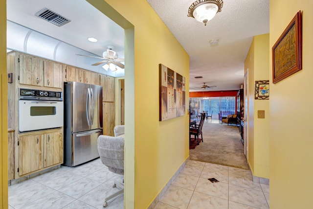 hallway with light carpet and light tile patterned flooring