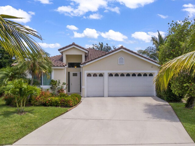 1235 SW Briarwood Dr, Port Saint Lucie, FL 34986 - view of front of house featuring an attached garage, a tiled roof, a front lawn, stucco siding, and concrete driveway
