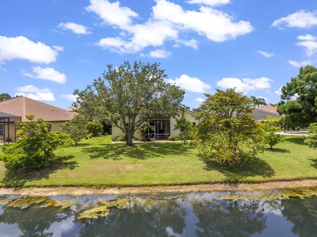 1235 SW Briarwood Dr, Port Saint Lucie, FL 34986 - back of house featuring a lawn, a water view, and stucco siding