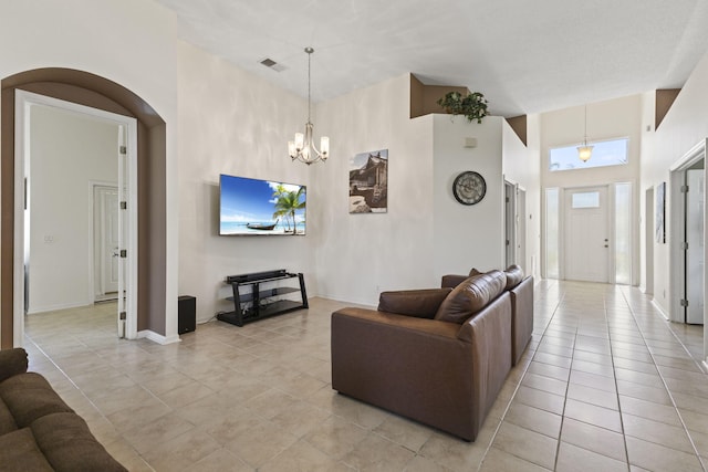 1235 SW Briarwood Dr, Port Saint Lucie, FL 34986 - living room featuring light tile patterned floors, a towering ceiling, arched walkways, a chandelier, and baseboards