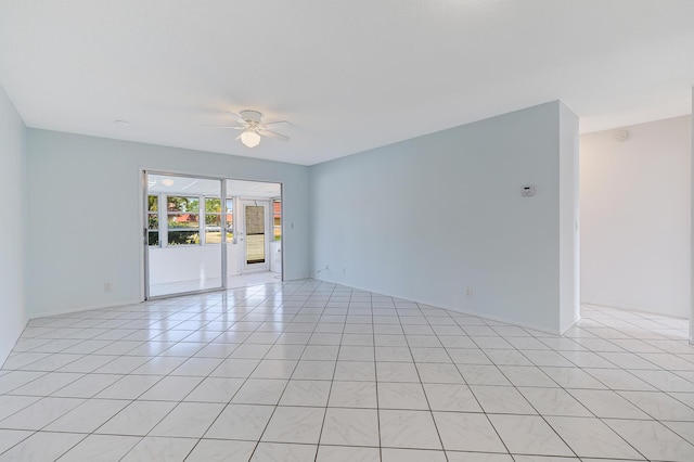 empty room with ceiling fan, light tile patterned flooring, and baseboards