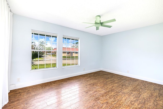 unfurnished room featuring baseboards, dark wood finished floors, and ceiling fan