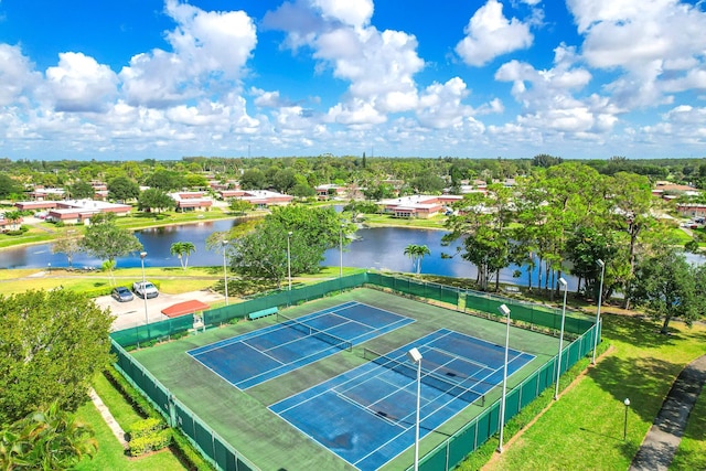 view of sport court with a water view and fence