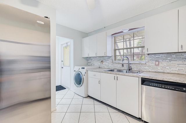 kitchen with washer / clothes dryer, stainless steel dishwasher, a sink, backsplash, and light countertops